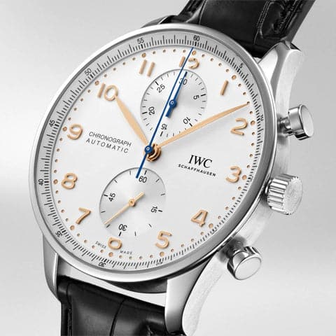 Close-up view of the IWC Portugieser Chronograph IW371604 watch, showcasing a white-silver-plated dial with golden feuillle hands and bi-compax chronograph counters. The stainless steel case is elegantly designed for a refined look, making it a perfect blend of form and function. This timepiece is finished with a sophisticated alligator leather strap.