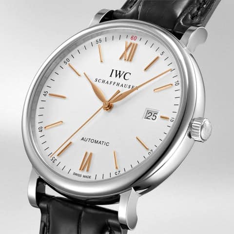 Close-up view of the IWC Portofino Automatic IW356517 watch, featuring a silver-plated dial with golden Roman numeral hour markers, refined stick markers, and signature feuillle hands, all protected by sapphire crystal. The elegant timepiece is complemented by a luxurious leather strap, showcasing IWC's craftsmanship and sophistication.